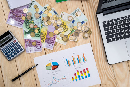Business chart with euro, laptop and calculator on deskの写真素材