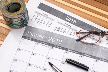 dollar with list for 2018 new year goals and pen