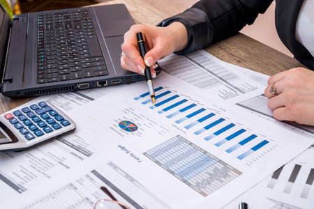 Business woman account annual budget with laptop, pen and graph.