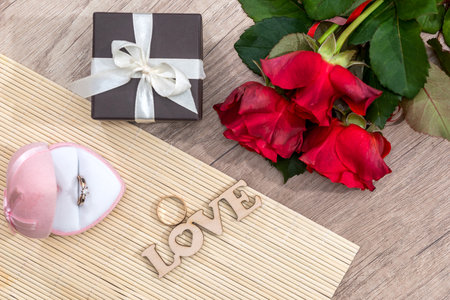 Wedding concept. text love with wedding rings, gift box and red roses