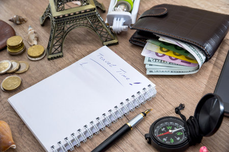 travel concept - empty notebook with pencil, euro and dollar in wallet, compass, seashell, phone, eiffel tower.の写真素材