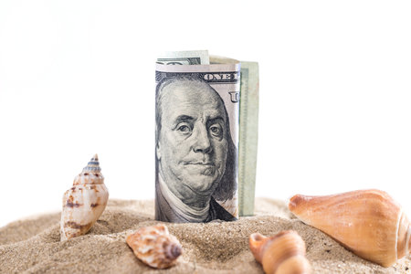 dollar in sand with shell isolated on white. summer conceptの写真素材