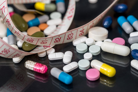 medical pills, vitamin tablets with measuring tape isolated on black background.の写真素材