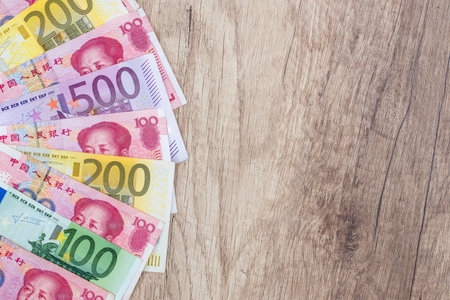yuan and Euro banknotes on wooden background.の写真素材