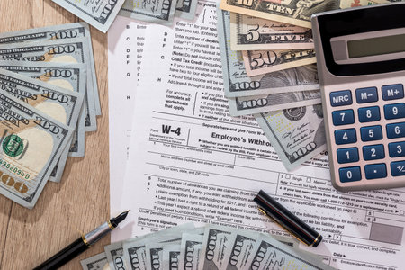 w4 tax form with money, pen and calculator on desk.の写真素材