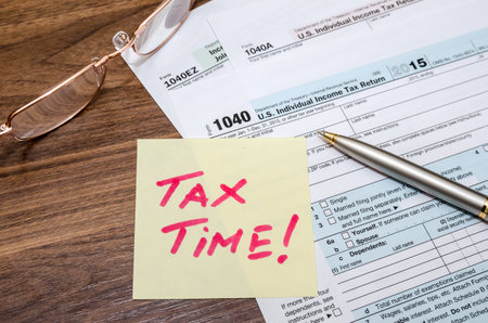 Tax time word on tax form with calculator, pen, glassesの写真素材