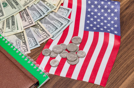 us dollar banknote with coins and flag, notepad, pen on tableの写真素材