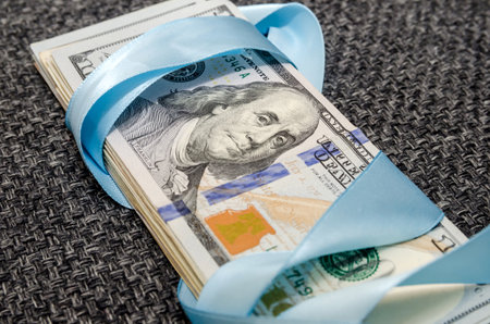 one hundred dollar bills in blue gift ribbonの写真素材