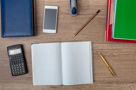 Calculator, notepads, pen and smartphone on wooden background