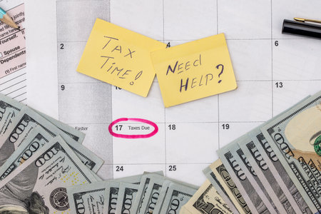 tax form with pen, calendar, money on deskの写真素材