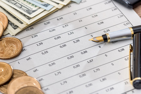 Dollar bills with business documents, pen and calculator as background.