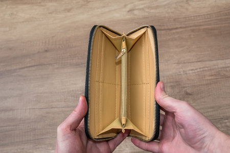 guy holding empty purse on desk