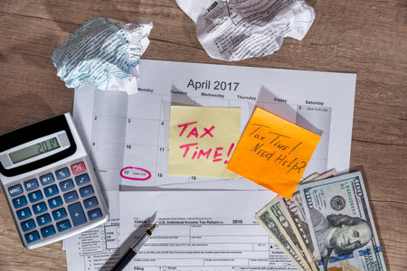 text "tax time" on tax forms 1040 with pen, calculator and money.の写真素材