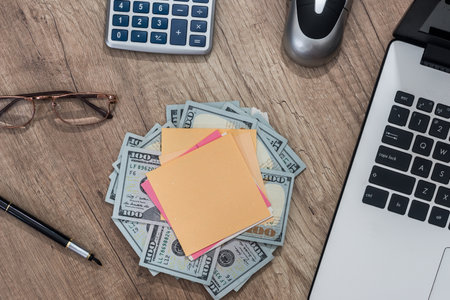 laptop, blank, notepad, calculator, dollar, pen on deskの写真素材