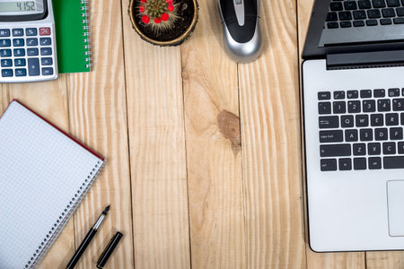 office desk with laptop, notepad, pen and calculator