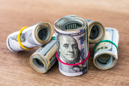 roll of dollars with rubber on desk.の写真素材