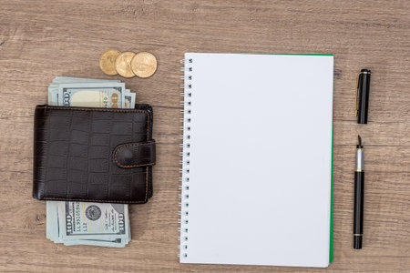 notepad with pen, calculator, dollar bills on desk.の写真素材
