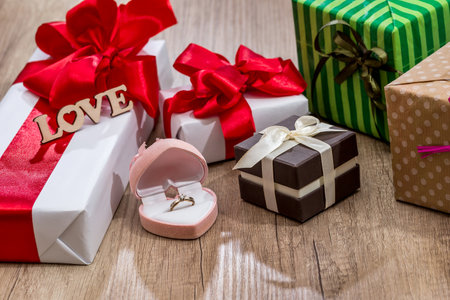 Many decorated gift boxes with ribbon bows and open box with gold ring