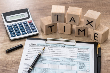 tax time - wooden cubes, foem, calculator and penの写真素材