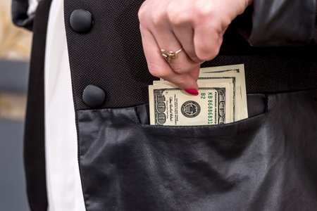 woman hiding dollars into the jacketの写真素材