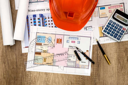 construction drawing with a calculator and a helmet on the table