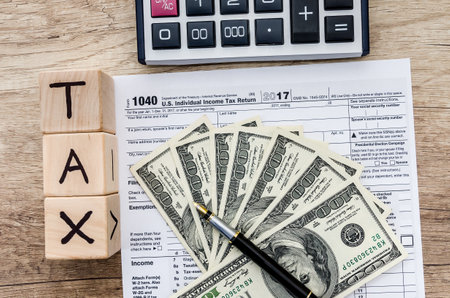 tax form with dollar, calculator and wooden cubes with text TAX
