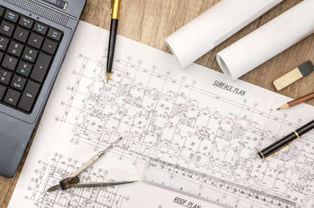 Laptop with blueprints dimensions on wooden desk