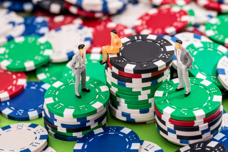 Small toy people are standing and sitting on poker chips