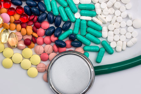 Stethoscope with colorful tablets on white background