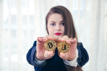 Selective focus on golden bitcoin in woman handsの写真素材