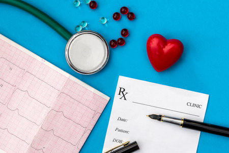 heart, stethoscope, cardiogram, pharmacy receipt and tablets are highlighted on a blue backgroundの写真素材