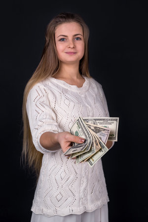 Beautiful woman proposing money or bribe isolated on blackの写真素材