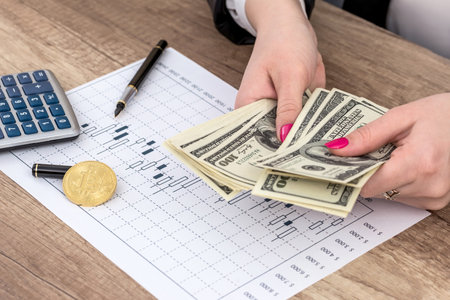female hand with dollar, bitcoin and business graphの写真素材
