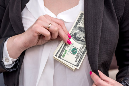 woman hiding dollars into the jacketの写真素材