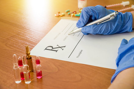 Doctor hands filling document with pills and syringe on deskの写真素材