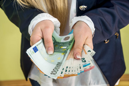 female holding euro in her hands isolated on greenの写真素材