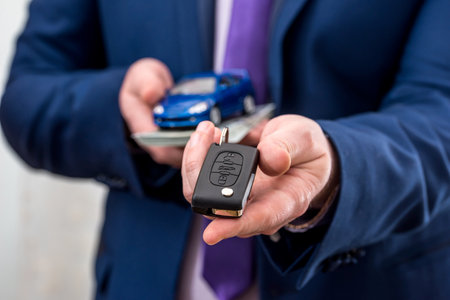 Businessman holding car key, toy car and moneyの写真素材