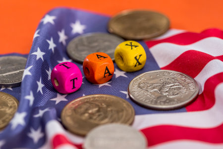wooden cubes tax with flag, dollar, coin and calculator on orange backgroundの写真素材