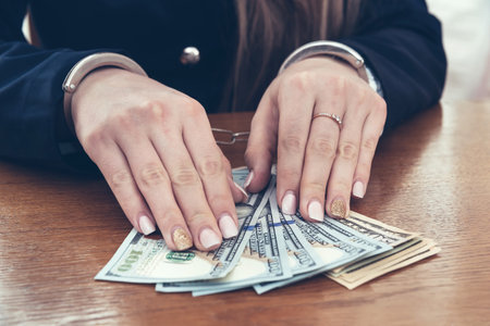 Hands of businesswoman in handcuffs with dollar notesの写真素材
