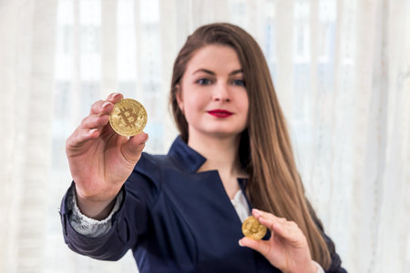 Selective focus on golden bitcoin in woman handsの写真素材