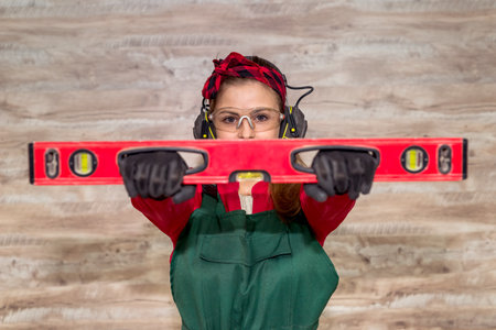 Selective focus on woman eyes with spirit level in carpentry