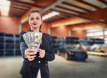 Woman with dollar notes and new car in service stationの写真素材