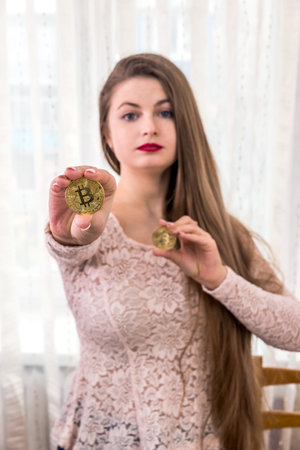 Pretty long hair woman showing two golden bitcoinの写真素材