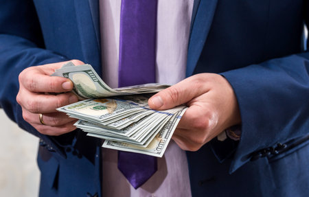 Man in suit counting dollar notes in his handsの写真素材