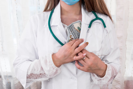 Doctor hiding dollar bribe into robe, corruption in medicineの写真素材