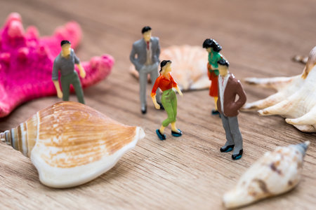 Small toy people are standing near seashell