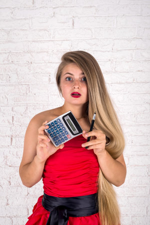 young woman holding calculator and pen in studioの写真素材