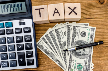 Wooden cubes TAX with money and calculatorの写真素材