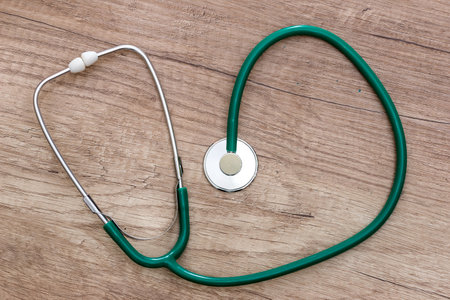 A green stethoscope is lying on a wooden tableの写真素材