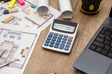Laptop with blueprints dimensions on wooden desk